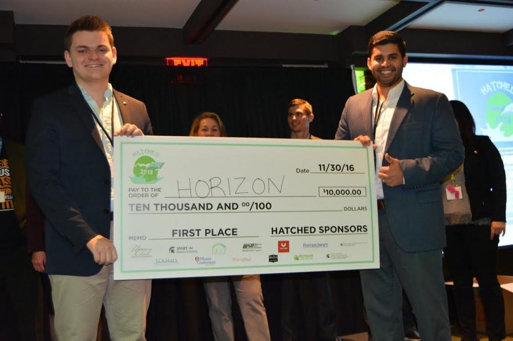 <p>Computer science sophomore Ben Buscarino and MSU alumnus Oshan Weerasinghe hold a check after winning a start-up competition.&nbsp;</p>