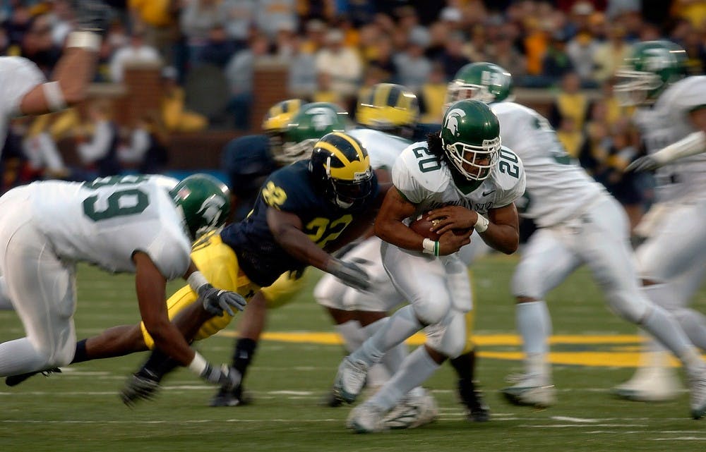 <p>Running back Jason Teague, 20, avoids a tackle from Michigan safety Jamar Adams, 22, on Oct. 30, 2004, in Ann Arbor. The Spartans lost to the Wolverines, 45-37, in triple overtime. Megan Gilshire/The State News</p>