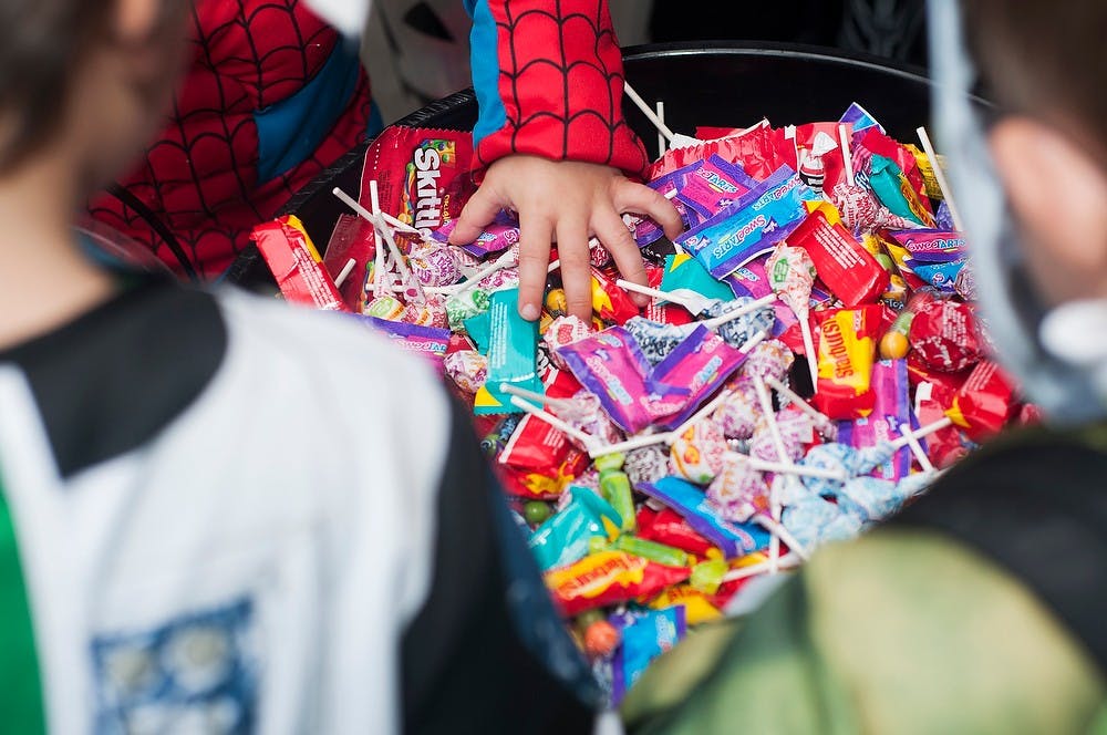 	<p>Trick-or-treaters grab candy during Trick-or-Treat on the Square, Oct. 28, 2013, on South Washington Square in downtown Lansing. Kids of all ages came out to participate in various activities while going from station to station for candy. Danyelle Morrow/The State News</p>
