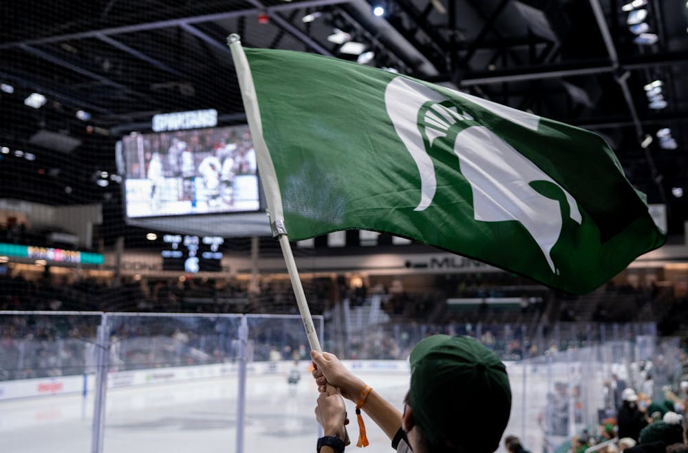 <p>A student section member waves a Spartan flag at the beginning of the third period. The Spartans fell to the Buckeyes, 4-1, at Munn Ice Arena on Jan. 21, 2022. </p>
