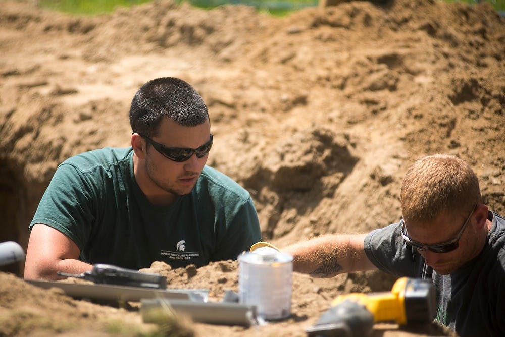 <p>East Lansing residents Raymond Rahall, left, and Josh Hamilton, right, repair pipes June 6 2014, at Munn Field. Munn Field is one of many areas on construction this summer. Hayden Fennoy/The State News </p>