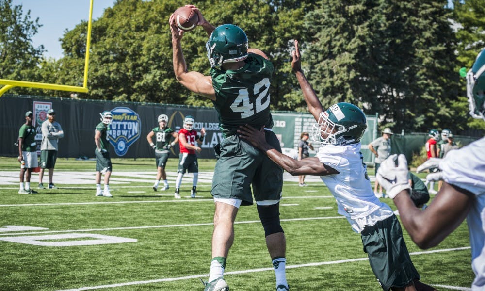 <p>Senior tight end Hussien Kadry (42) catches the ball while performing a drill during the football practice on July 31, 2017, at the practice fields behind the Duffy Daugherty Football Building</p>