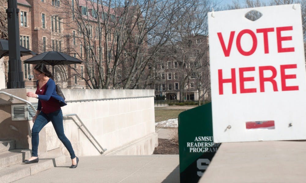 Communication senior Kim Nguyen walks by a voting sign on March 8, 2016 on the steps of the MSU Union. Nguyen voted earlier today in the Michigan presidential primary election.