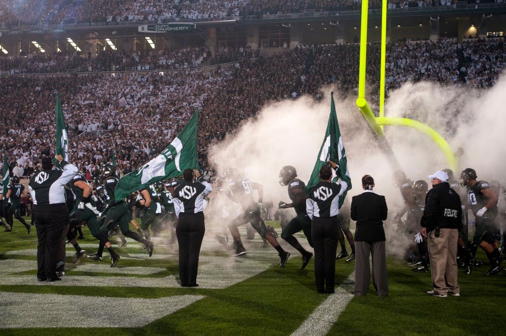 <p>The Spartans enter the stadium in a cloud of smoke at the start of the game against Oregon on Sept. 12, 2015 at Spartan Stadium. The Spartans defeated the Ducks 31-28. Catherine Ferland/ The State News</p>
