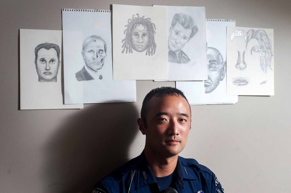 Officer Casey Christman, special reaction team operator and forensic artist for the MSU Police, stands with his sketches inside of the police station on Tuesday night, July 31, 2012. Christman said he was asked to do the job after he doodled someone that was arrested when he was bored. Natalie Kolb/The State News