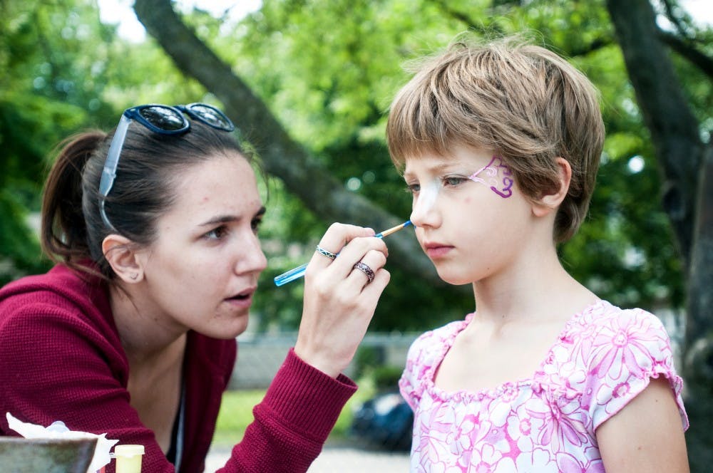 Marie Adele Grosso, 7, of East Lansing gets her face painted by Karyn Thrush of Okemos during Pumpstock, Saturday, June 2, 2012 at the East Lansing Bailey Community Center.  Saturday marked the thrid annual Pumpstock event.  Adam Toolin/The State News