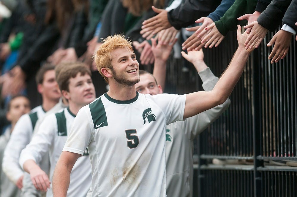 <p>Then-junior defender Zach Carroll gives fives to Spartan supporters Nov. 23, 2014, after the game against Oakland at DeMartin Stadium at Old College Field. The Spartans defeated the Golden Grizzlies, 1-0. Aerika Williams/The State News </p>
