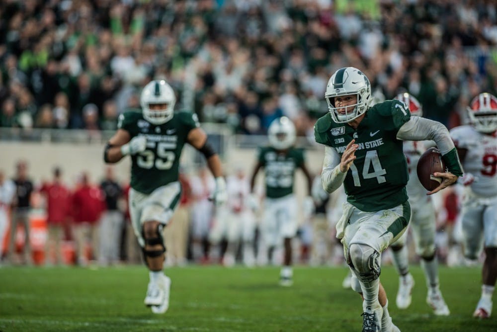 Senior quarterback Brian Lewerke (14) runs the field during the homecoming game against Indiana on Sept. 28, 2019 at Spartan Stadium. The Spartans beat the Hoosiers, 40-31.