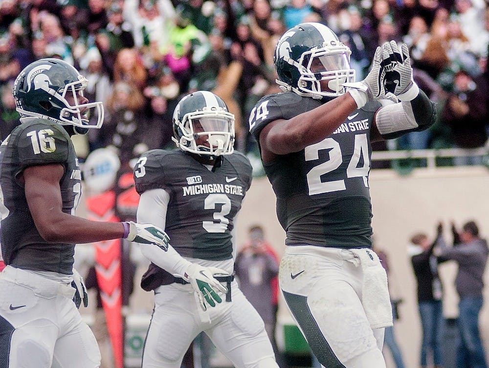 	<p>Junior running back Le’Veon Bell celebrates by showing the Spartan logo with his gloves after scoring a touchdown Nov. 3 at Spartan Stadium. Adam Toolin/The State News</p>