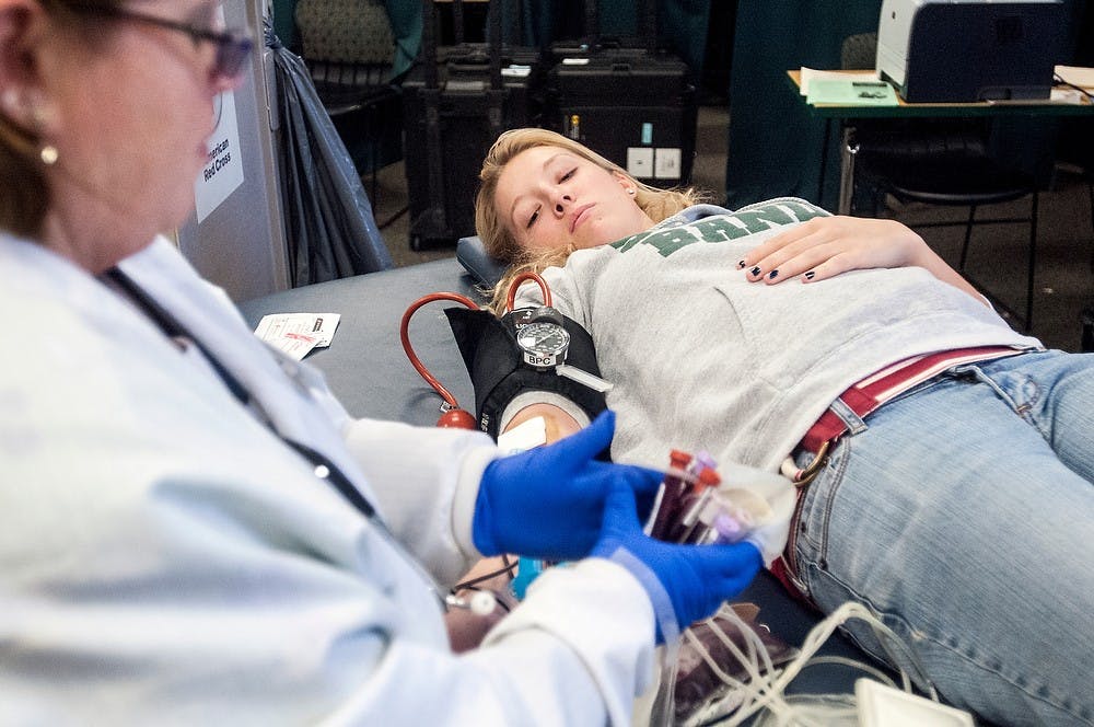 	<p>Advertising junior Angela Wright gives blood as collections technician Michelle Case organizes the donations Jan. 23, 2013, at the International Center. Students, faculty and East Lansing residents all came out to donate blood. Adam Toolin/The State News</p>