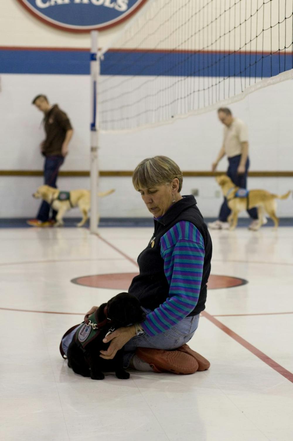 Carol McEllhiney-Luster works with Bess on the floor of Emanuel First Lutheran Church, 1001 N. Capitol Ave. During training sessions, puppies and older dogs work separately so they can work on different skills. Matt Radick/The State News