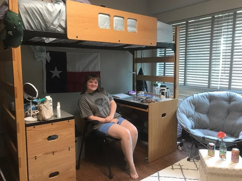 <p>Hospitality Business freshman Rachel Powell sits in her dorm room with her one piece of decor; her Texas flag. Courtesy of Rachel Powell.</p>