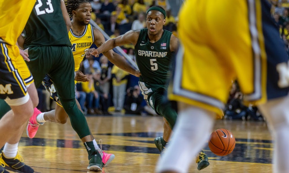 Junior guard Cassius Winston (5) drives on Michigan's Zavier Simpson. The Spartans beat the Wolverines, 77-70, on Feb. 24, 2019 at the Crisler Center.