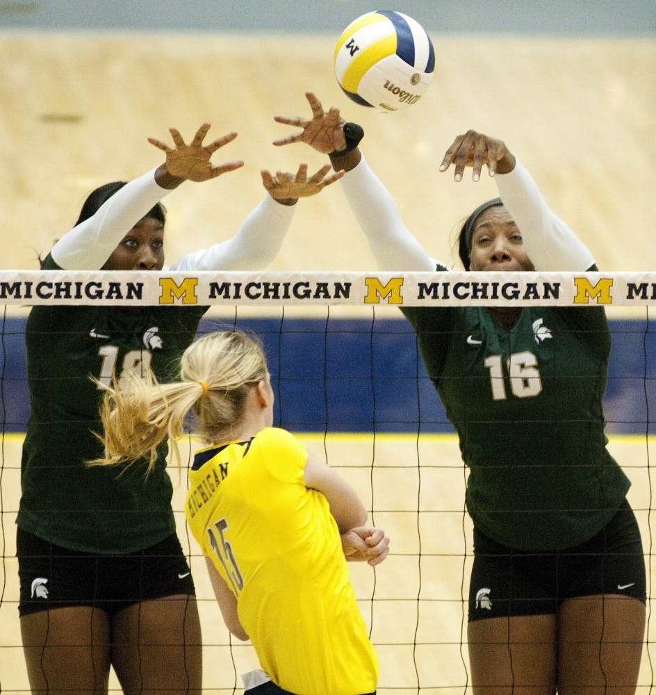 Redshirt sophomore middle blocker Alexis Mathews and senior outside hitter Kyndra Abron go up to block the ball spiked by U-M middle blocker Courtney Fletcher. The Spartans lost to the Wolverines, 3-1, on Wednesday evening at Cliff Kreen Arena in Ann Arbor. Josh Radtke/The State News