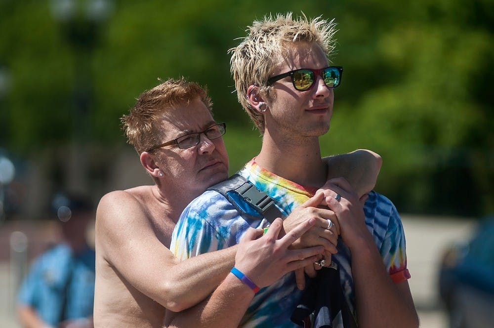 <p>From left, Haslett, Mich., residents Mark Cook and Josh Taylor watch Michigan politicians speak about LGBT rights during a commitment ceremony held by Michigan Pride on Aug. 23, 2014, at the Capitol building in Lansing. Jessalyn Tamez/The State News</p>