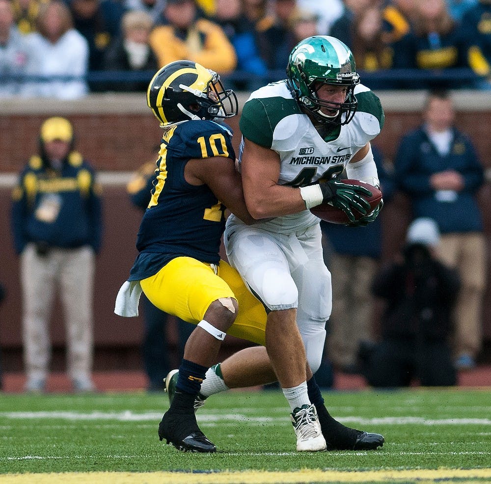 	<p>Junior linebacker Max Bullough intercepts a ball by Michigan quarterback Denard Robinson as he is being tackled by Michigan wide receiver Jeremy Gallon that ends the first half that trails Michigan, 6-0, on Oct. 20 at Michigan Stadium in Ann Arbor, Mich. Justin Wan/The State News</p>