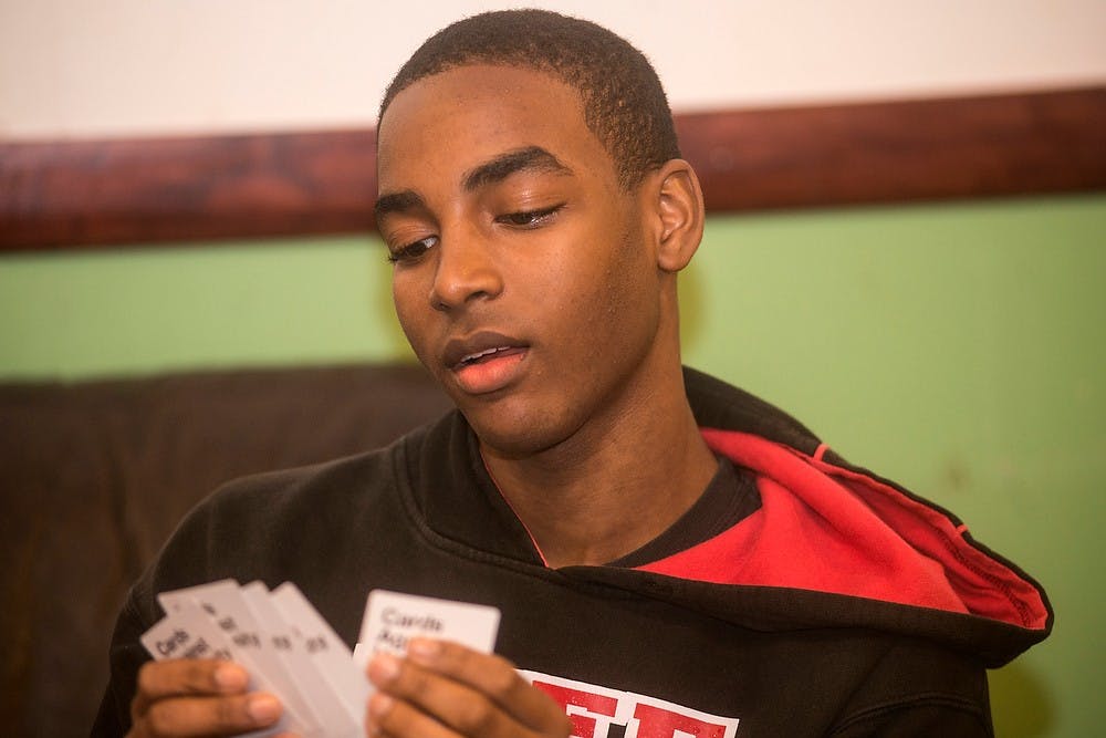 <p>Undecided freshman Derrick Dawson looks at his cards Sept. 15, 2014, during a game of Cards Against Humanity with the Delta Lambda Phi fraternity at Bubble Island on Grand River Avenue. Delta Lambda Phi is a fraternity primarily for gay men or those who are male identified. Erin Hampton/The State News</p>