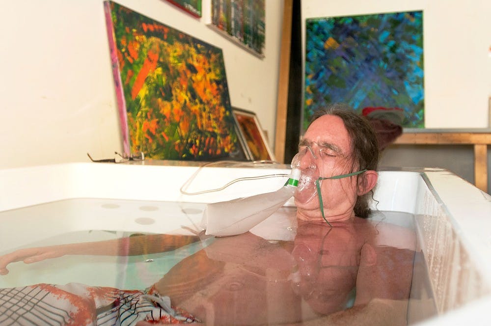 	<p><span class="caps">MSU</span> alum and owner of Hotwater Works, James McFarland, relaxes inside of a 116 degree soaking tub and breathes from an oxygen tank Tuesday, inside of the store located at 2116 E. Michigan Ave. in Lansing. Natalie Kolb/The State News</p>