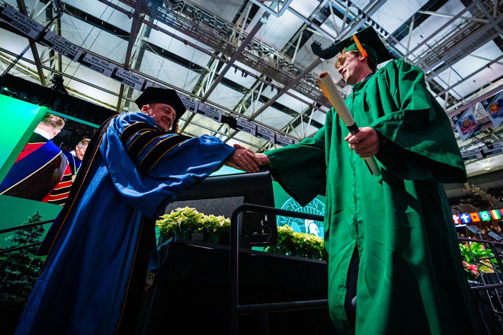 An MSU alumnus shakes a professor's hand during the fall 2024 commencement ceremony at the Breslin Center on Dec. 14, 2024.