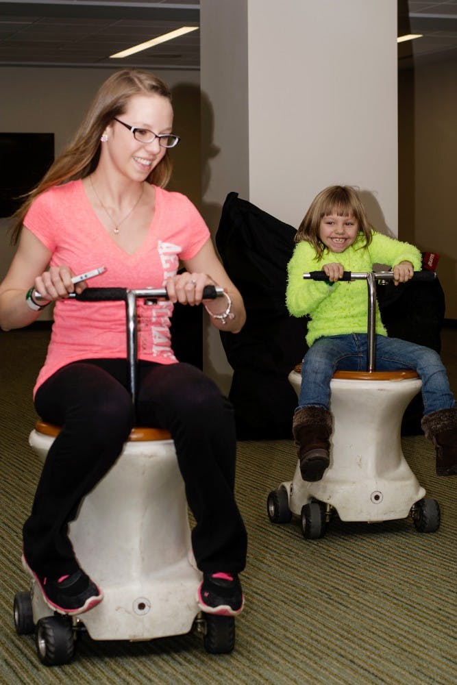 <p>Zoology senior Brooke Wohlers and Sturgis, Mich., resident Brielle Wohlers, 6, "potty race" during Little Sibs Weekend on Feb. 7, 2014, at the Union. The annual event was comprised of two days worth of activities and was organized by the UAB. Casey Hull/The State News</p>