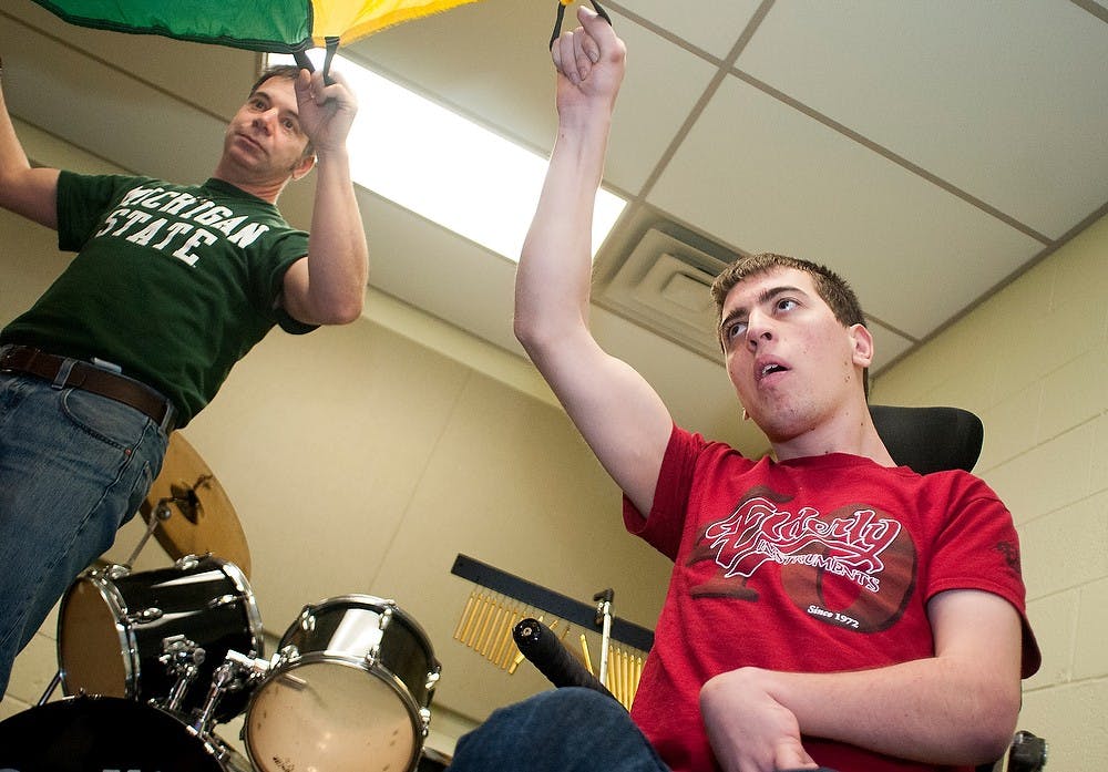 	<p>Michigan State University Community Music School student, Evan Fiorella, right, and stepfather Chris Calaguiro lift a parachute at the adult music therapy class on Wednesday, Jan. 31, 2013 at the Music School. Evan helps plan this class every week. Katie Stiefel/The State News</p>