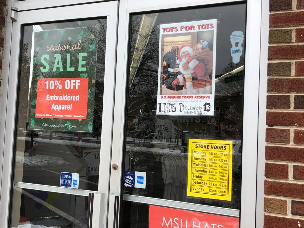 <p>A Toys for Tots poster sits in the window of Campus Corner on Grand River Avenue. Photo by Maisy Nielsen</p>