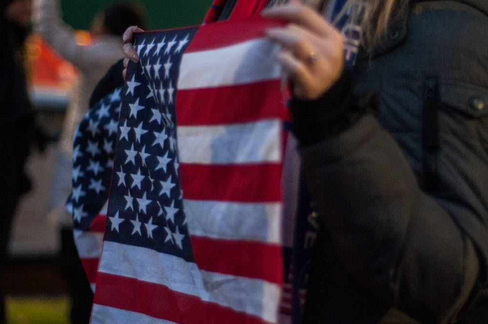 A protester holds an American flag during a "Trump is Not Above the Law" protest at Grand River and Abbott in East Lansing on Nov. 8, 2018.