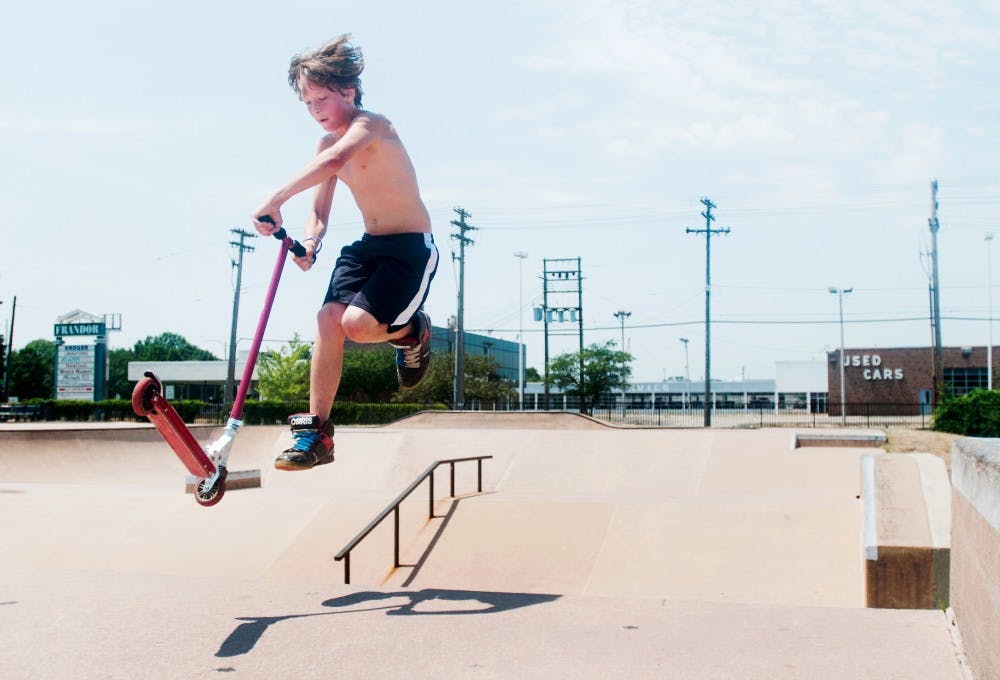 Thirteen-year-old Johnny Dzik, from Charlotte, Mich., does a trick on his scooter while hanging out with friends at Ranney Skate Park, 3201 E. Michigan Ave., in Lansing on Monday. Dzik and two of his friends spent the hot afternoon practicing tricks and enjoying the skate park. Samantha Radecki/The State News