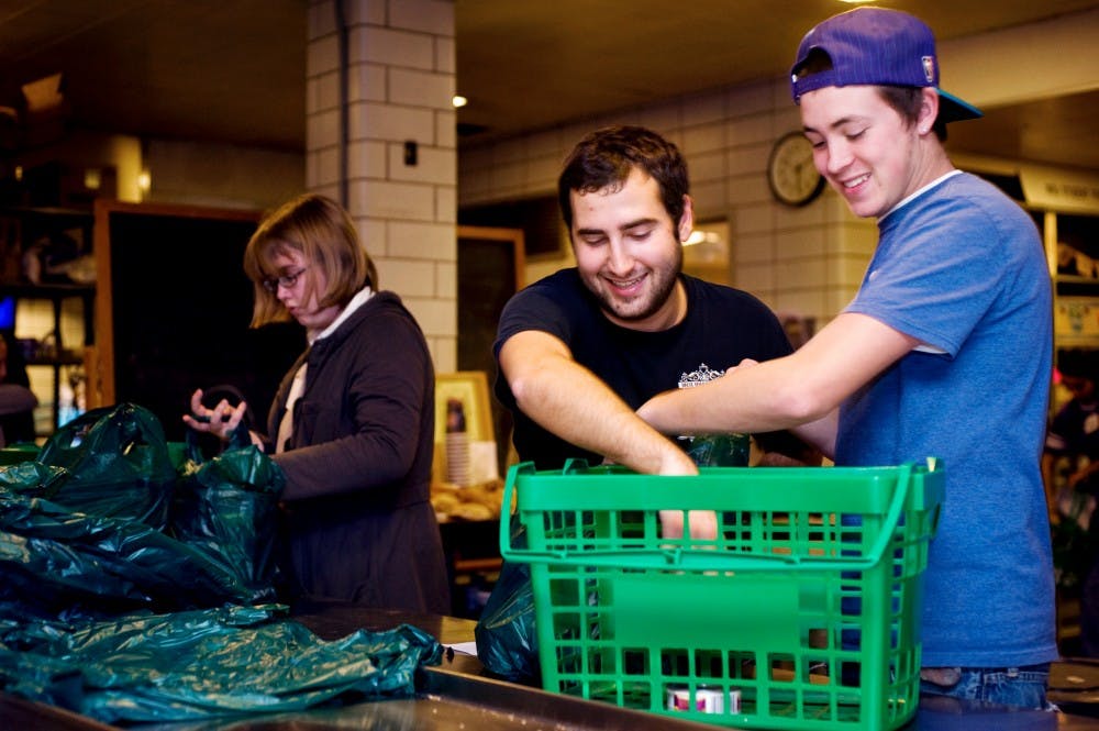 Physiology senior Alex Hoelzel, left, and kinesiology junior Justin Collins, right, volunteer and bag up food at the MSU Student Food Bank on Wednesday evening. Lauren Wood/The State News