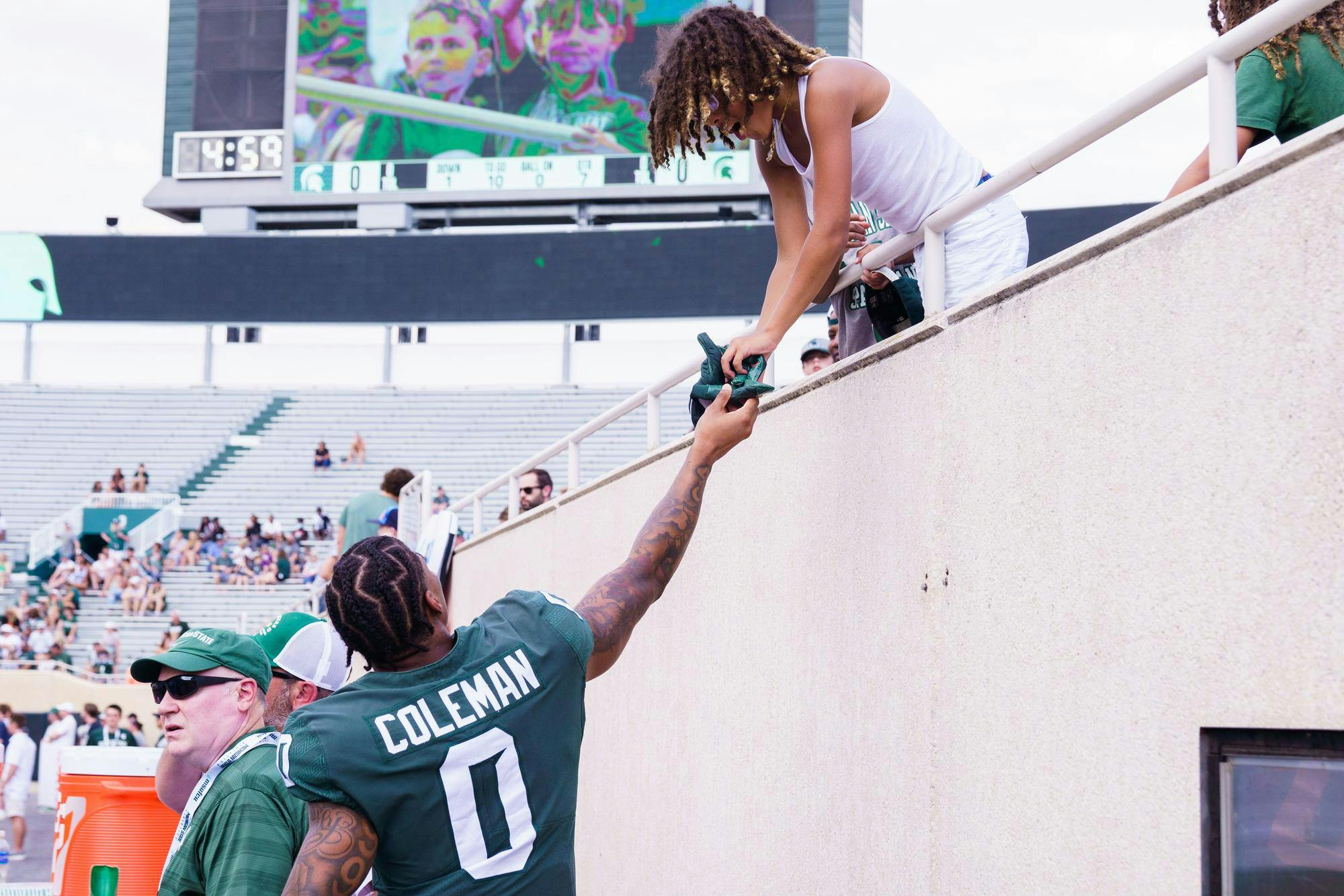 Junior wide receiver Keon Coleman (0) hands his gloves to a young fan during the MSU football spring open practice, held at Spartan Stadium on April 15, 2023.