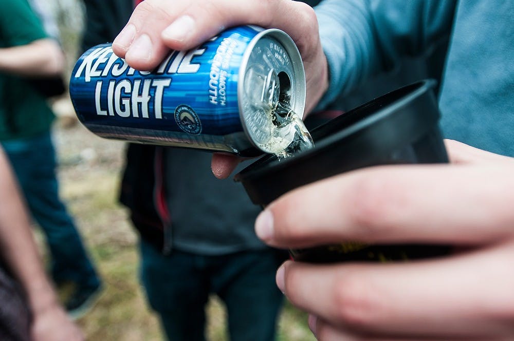 <p>Ferris State University student Alex Kallenbach pours beer into a cup April 12, 2014, at Nachofest at a house on Stoddard Ave. Nachofest is an annual party where tortilla chips and nacho cheese are provided. Erin Hampton/The State News</p>