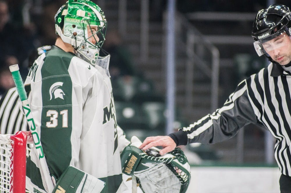 Sophomore goalie John Lethemon (31) hands the ref the puck after a close save during the first period of the men's hockey game against Minnesota on Jan. 18, 2018 at Munn Ice Arena. The Spartans and Gophers were tied 1-1 in the first period. 
