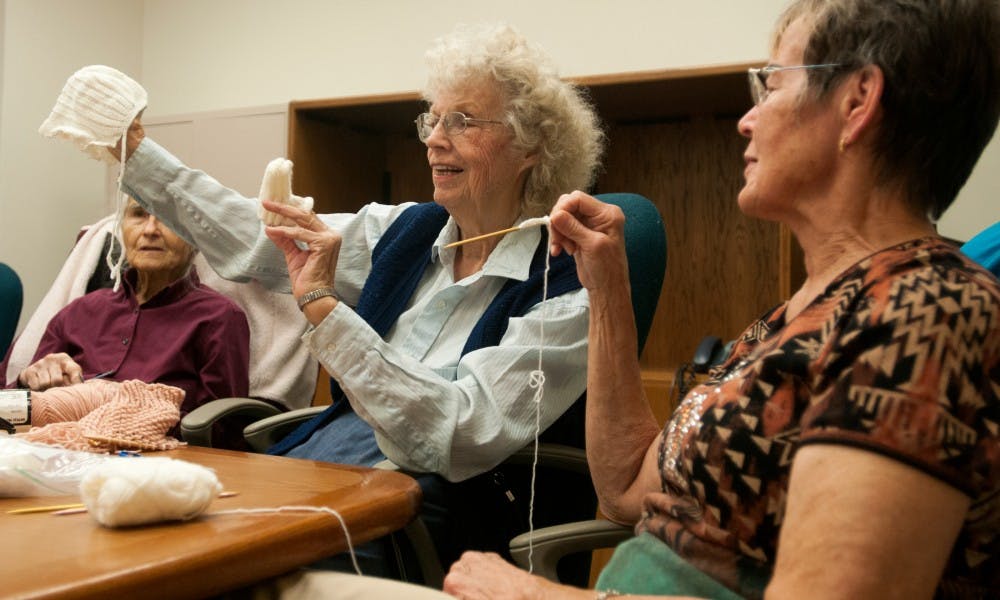 <p>From left to right, Mason resident Edna Eckert, Lansing resident Nina McQueen and Holt resident Jane Johnson admire a hat and booties that Johnson knitted for a local pregnancy center on Oct. 20, 2015 at the Nisbet building, 1407 South Harrison Road, in East Lansing. The group of retired ladies have been meeting to knit for local hospitals, pregnancy centers and homeless shelters for the past 20 years and have donated over 26,000 items in that time. </p>