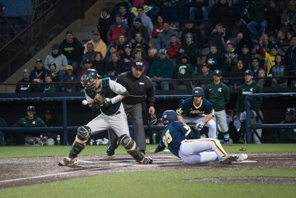 Junior catcher Matt Byars (28) drops the throw allowing junior outfielder Johnny Slater (25) to score a run during the game against Michigan on April 29, 2016 at Ray Fisher Stadium at Wilpon Baseball Complex in Ann Arbor, Mich. The Spartans were defeated by the Wolverines, 4-3.