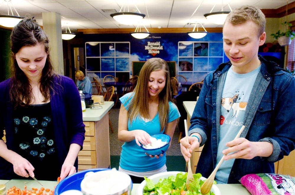 Nutritional sciences students, from left, sophomore Ashley McNamara, junior Liz Ostergaard and junior Dan Bator prepare a salad as part of the meal they make for residents of the Ronald McDonald House, 121 S. Holmes St., on Thursday in Lansing. The students are all members of the Nutritional Sciences Club, which volunteers by regularly cooking meals for the families staying at the house. The Ronald McDonald House provides temporary and affordable housing for families with a child or loved one receiving treatment at Sparrow Hospital. Kat Petersen/The State News