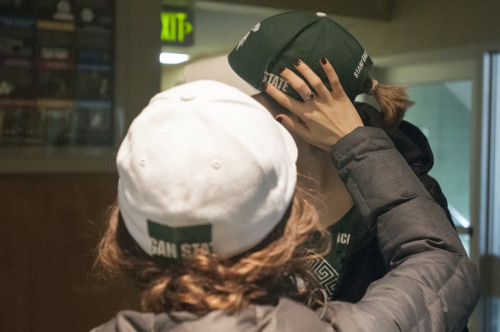 Physiology sophomore Sena Al-Ado,left, puts tape over the Nike logo on physiology sophomore Abby Meyers hat on Nov. 16, 2016 in East Shaw Hall. Al-Ado and Meyer are part of United Students Against Sweatshops which delivered a letter to the Office of the President requesting that MSU confront Nike about allegations of worker's rights violations.