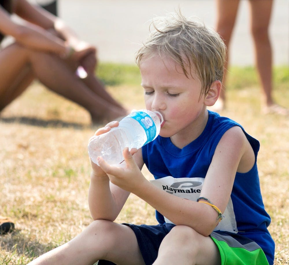 Seven-year-old Gabe Regan of Lansing drinks a bottle of water after running a 5k with his father at Lansing's Hawk Island County Park on Sunday morning, July 15, 2012. The 5k was put on to raise money for the Lansing Area AIDS Network. Natalie Kolb/The State News