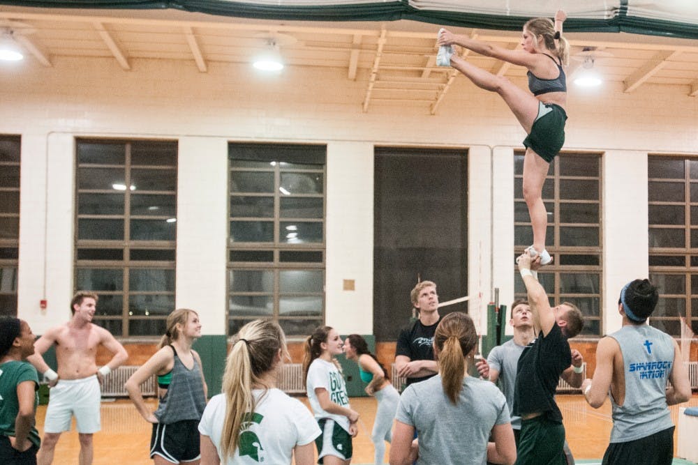 Members of the MSU Cheerleading Team hit a stunt during the MSU Cheerleading Team practice on Feb. 28, 2017 at Jenison Field House. 