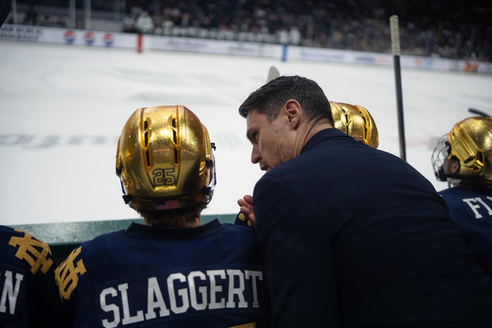 Carter Slaggert (25) receives words from Brock Sheahan, head hockey coach of University of Notre Dame, on the bench during a game against Michigan State at Munn Ice Arena in East Lansing, Michigan, on Friday, Feb. 20, 2026.