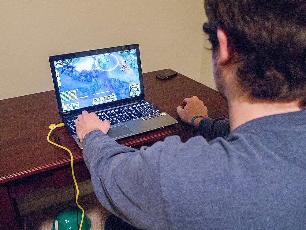 <p>Supply chain management sophomore Tim Cummings enjoys an evening of gaming Nov. 26, 2014, in his home. Tim avidly plays League of Legends, a popular online multiplayer game. Dylan Vowell/The State News</p>