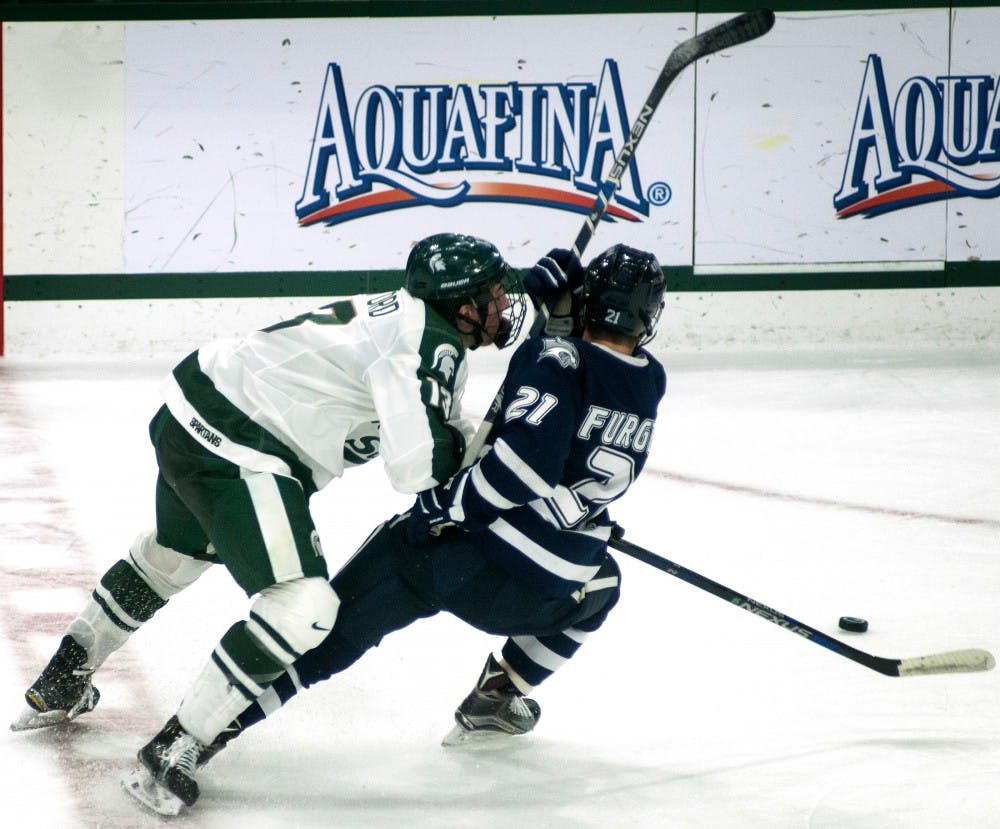 <p>Freshman forward Brennan Sanford goes up against New Hampshire defenseman John Furgele in hopes of securing the puck during the first period of the game against New Hampshire on Nov. 7, 2015, at Munn Ice Arena. The Spartans defeated the Wildcats, 7-4. </p>