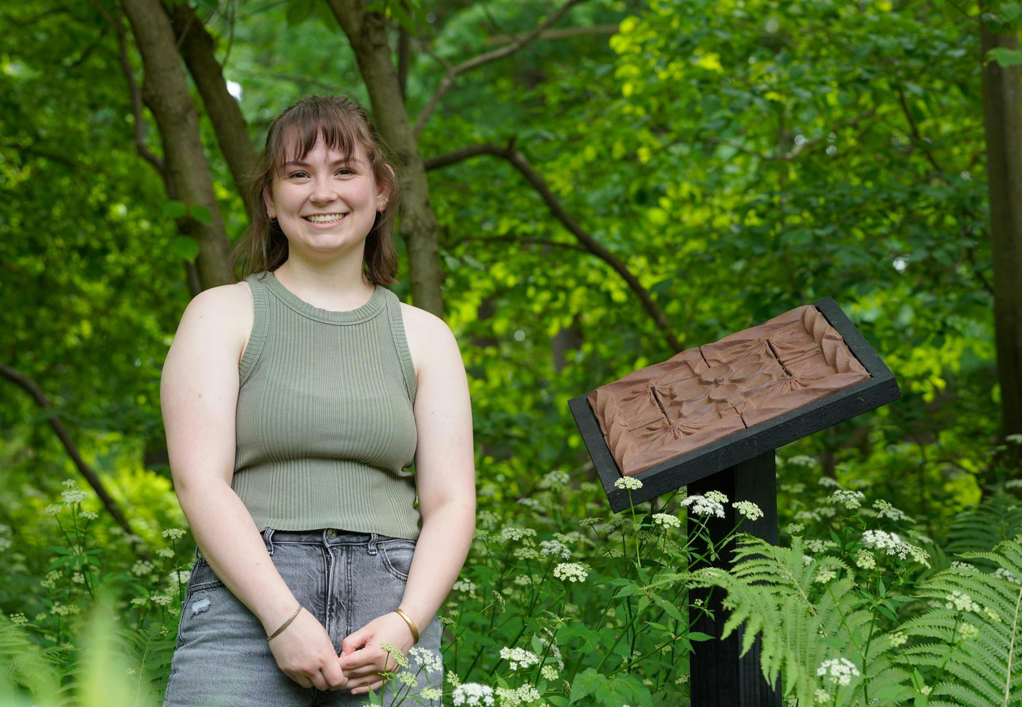 MSU BFA student Ellie Stanislav stands next to "Magnolia Transplanted" at the Beal Botanical Garden on May 24, 2024.