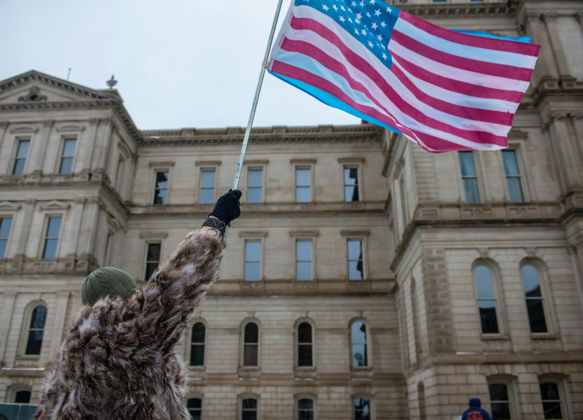 Micheala Hundersmarck, 31, of Grand Rapids, waves a Transgender and American flag during the Women’s March On Lansing 2020 Jan. 18, 2020, hosted by the Blue Brigade.
