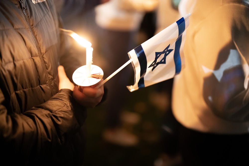<p>A hand-held candle and the flag of Israel on display at the vigil held at Spartan Statue in observance of the war in Israel-Gaza, on Oct. 9, 2023.</p>
