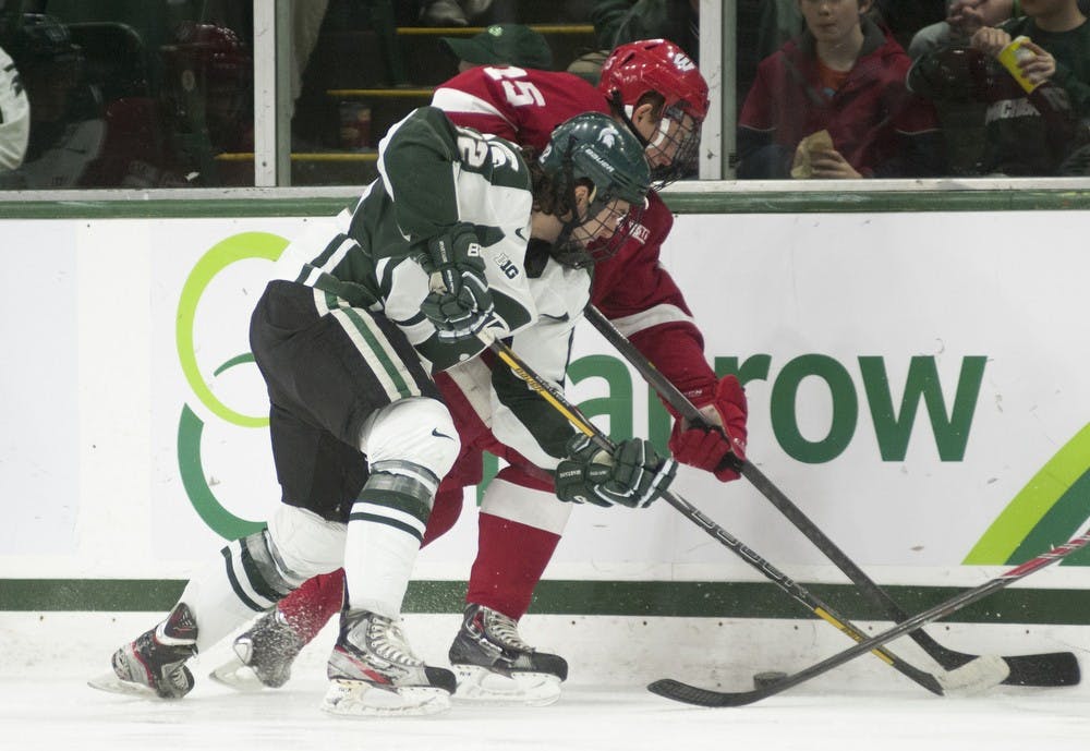 <p>Senior forward Lee Reimer fights for the puck along the boards against Wisconsin forward Morgan Zulinick on March 14, 2014, at Munn Ice Arena. The Spartans defeated the Badgers, 5-4, after a goal by Reimer 46 seconds into overtime. Danyelle Morrow/The State News</p>