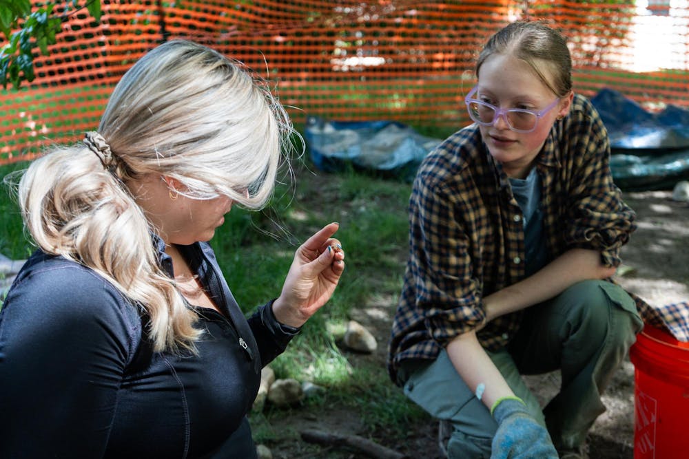 <p>Gabrielle Moran-O'Dell (left), a third-year graduate student and student campus archaeologist for MSU's Campus Archaeology Program, identifies a rock that undergraduate student Deanna Peterson (right) asked her about while working on the old observatory site&nbsp;in East Lansing, Mich., on June 15, 2026.</p>