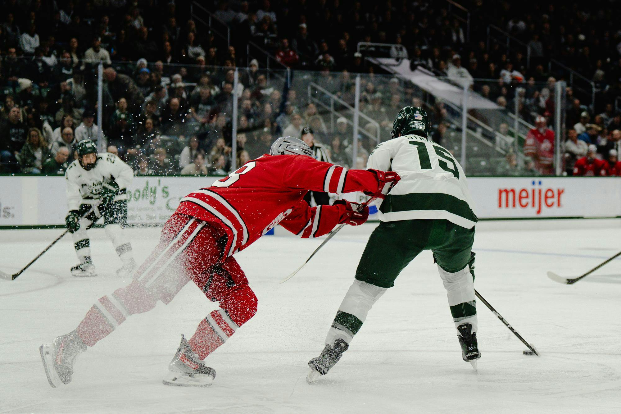 <p>MSU junior forward Charlie Stramel (15) braces a check from an Ohio State defender in a game at Munn Ice Arena on Nov. 8, 2024</p>