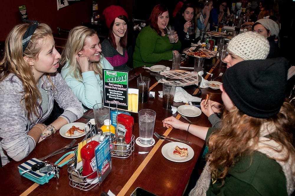 <p>From left, MSU Women's Glee Club members, theatre junior Kendall Kotcher, zoology senior Lauren Mulcrone, and journalism freshman Brooke Marriott  enjoy a pizza together with friends Nov. 19, 2014, at Peppino's Sports Grill. Peppino's Sports Grill bartender and Haslett, Michigan resident Heather Nelson recommends the cheesy bread. "It's the best thing on the menu in my opinion," Nelson said. Raymond Williams/The State News</p>