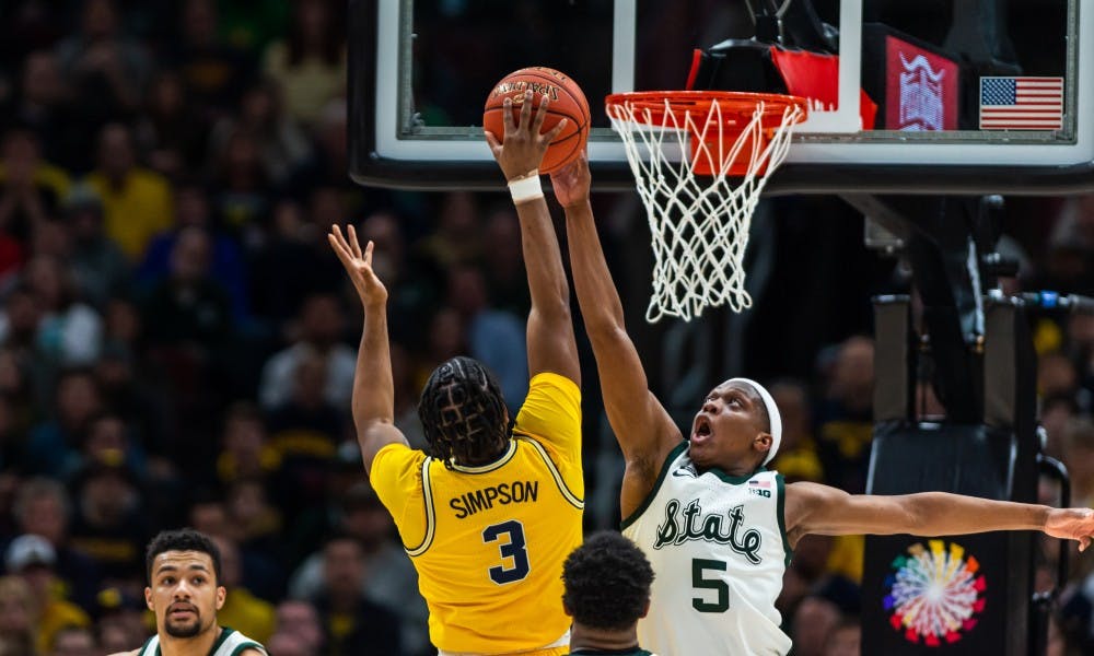 Junior guard Cassius Winston (5) blocks a shot from Michigan's Zavier Simpson. The Spartans beat the Wolverines, 65-60, at the United Center on March 17, 2019.