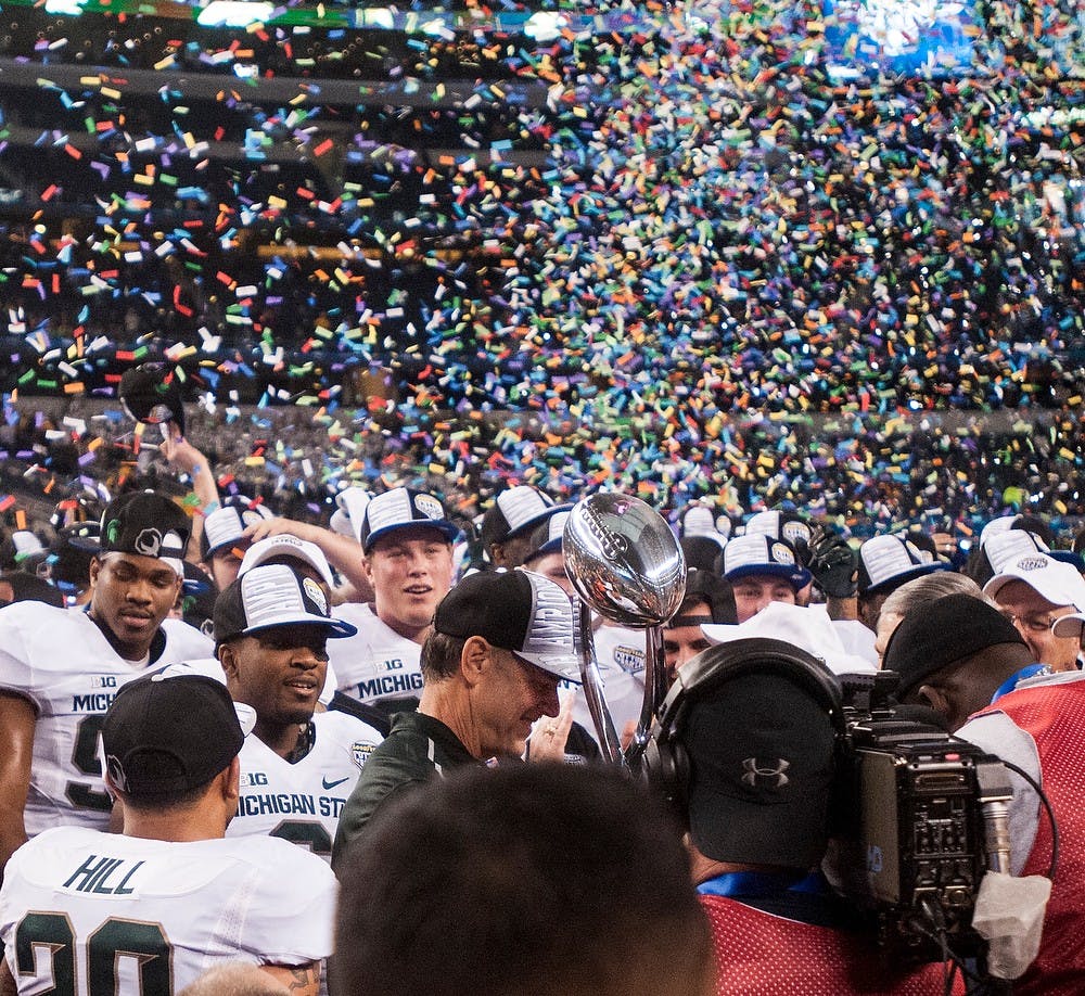 <p>Head coach Mark Dantonio holds the trophy and celebrates the win with his team Jan. 1, 2015, during The Cotton Bowl Classic football game against Baylor at AT&T Stadium in Arlington, Texas. The Spartans defeated the Bears and claimed the Cotton Bowl Victory, 42-41. Erin Hampton/The State News</p>